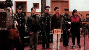 Zhiwen Wang (au micro à gauche) est jugé avec trois autres pratiquants de Falun Dafa. Ce simulacre de procès était destiné à influencer d'autres pratiquants, afin de les convaincre d'abandonner cette discipline spirituelle. (crédit photo: Ffamille Wang)