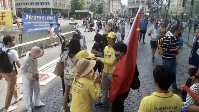 Plusieurs militants pro-CCP masqués, dont un portant une chemise sur laquelle on peut lire "Chine", perturbent une manifestation pacifique en faveur du Falun Gong à Bruxelles, en Belgique, le 26 juin 2023. L'un d'eux porte un grand drapeau communiste chinois