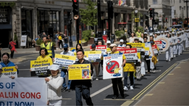 Monsieur Hu Xuanming (2e rang, à droite), dont la mère est emprisonnée en Chine, participe à un rassemblement commémorant le 24e anniversaire de la persécution du Falun Gong par le régime chinois, à Londres, le 15 juillet 2023. (via Yanning Qi/The Epoch Times)